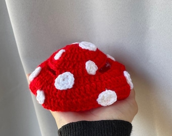 May include: A red crocheted mushroom with white polka dots.