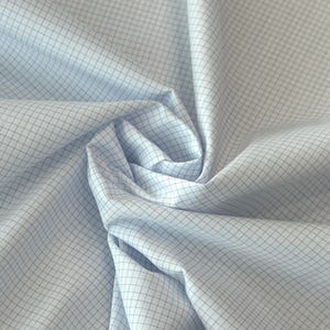 Könnte beinhalten: Nahaufnahme eines hellblauen Stoffes mit einem Gittermuster. Der Stoff ist gerafft und gefaltet, wodurch ein wirbelnder Effekt entsteht. Die Gitterlinien sind in einem helleren Blauton gehalten, was einen subtilen Kontrast erzeugt. Der Stoff wirkt weich und glatt.