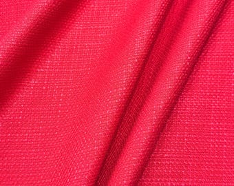 May include: Close-up of a vibrant red fabric with a textured weave. The material is draped, creating soft folds and shadows. The colour is a bright, solid red, filling the frame.