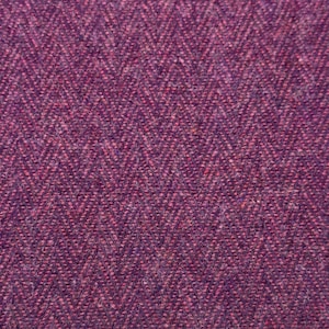 Könnte beinhalten: Eine Nahaufnahme eines gewebten Stoffes mit einem ausgeprägten Fischgrätenmuster. Das Textil zeigt eine satte, tiefviolette Farbpalette mit subtilen Tonvariationen, die durch das Verweben von dunklen und helleren violetten Fäden entstehen.