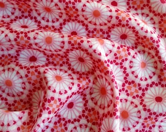 Pode incluir: Close-up de um tecido com um padrão floral repetitivo. O design apresenta flores brancas, rosa e vermelhas com centros laranja, sobre um fundo rosa. O tecido é drapeado, mostrando a textura e o fluxo do material.