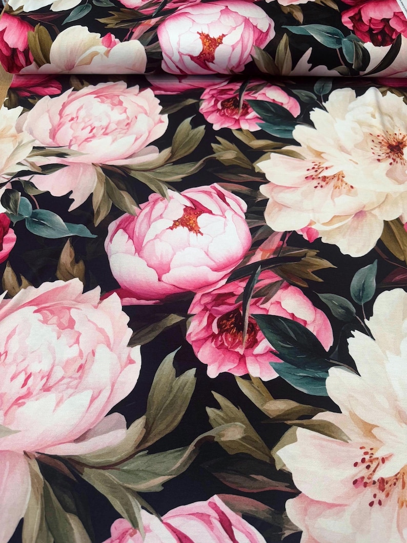 Pode incluir: Tecido floral com grandes pe&oacute;nias rosa e creme sobre um fundo escuro. As pe&oacute;nias t&ecirc;m p&eacute;talas detalhadas e s&atilde;o rodeadas por folhas verdes, criando um design bot&acirc;nico exuberante.