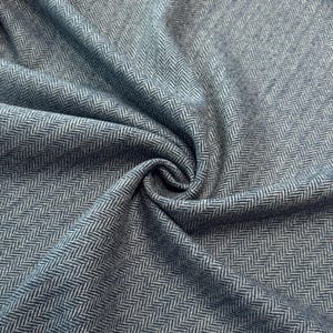 May include: A woven fabric featuring a classic blue and white herringbone pattern. The material is gathered in the centre, creating soft folds and shadows that highlight the intricate V-shaped weave texture throughout the entire surface area.