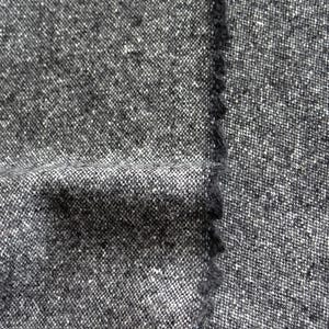 May include: Close-up of a textured fabric in shades of gray and white. The material has a woven appearance with a slightly rough texture. The edge of the fabric is visible, showing a raw, unfinished edge.