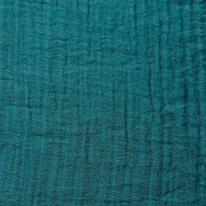 May include: Close-up of a teal-colored fabric with a textured, crinkled appearance. The fabric has a soft, flowing drape, with vertical and horizontal lines creating a subtle grid pattern. The color is a deep, saturated teal.