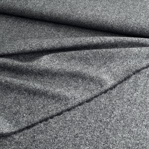 May include: Close-up of a gray fabric with a textured surface. The fabric is folded and draped, creating shadows and highlighting the material's texture. The fabric appears to be a medium-weight material, suitable for various sewing projects.