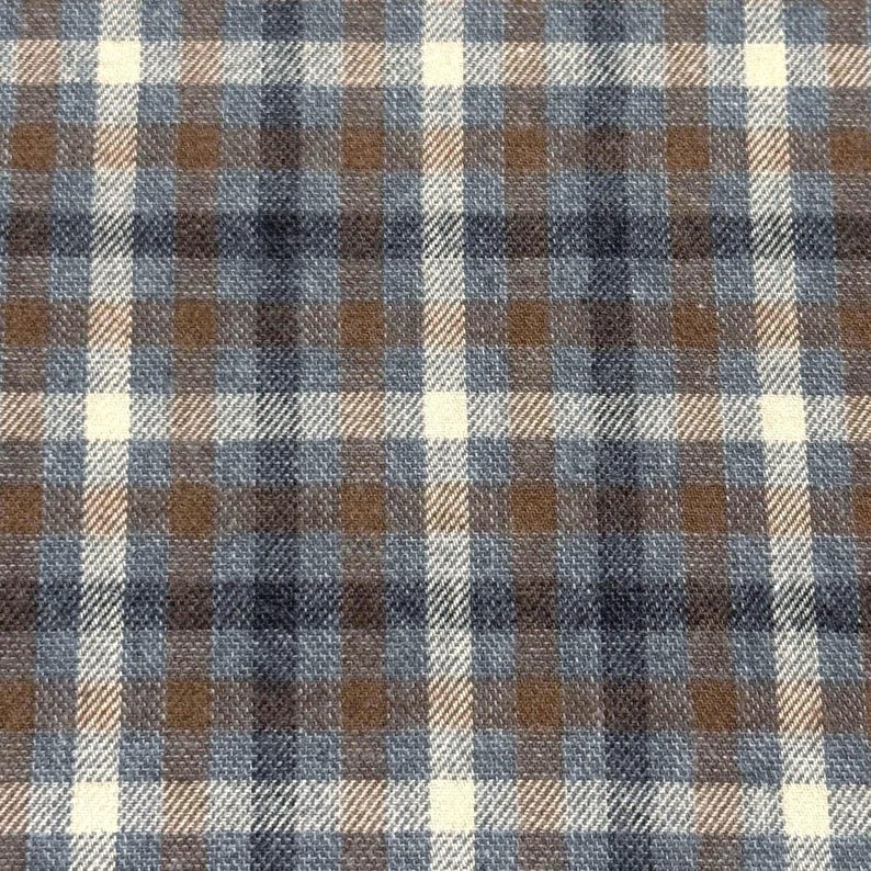 May include: Close-up of a fabric with a plaid pattern. The design features a grid of intersecting lines in cream, brown, and shades of blue. The fabric has a textured appearance, suggesting a woven material.