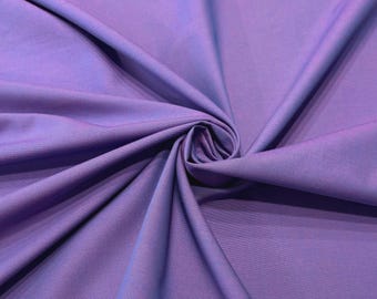 Pode incluir: Um tecido de cor violeta claro sólido com uma textura suave e mate. O material está reunido no centro, criando pregas profundas e radiantes e sombras suaves que destacam a cor consistente e a trama fina da superfície do tecido.