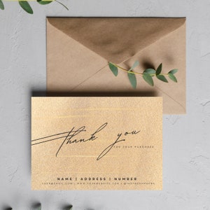 Puede incluir: Tarjeta de agradecimiento dorada con texto en cursiva negra que dice "Gracias por su compra". La tarjeta tiene un acabado sutil de brillo e incluye espacio para un nombre, una dirección y un número de teléfono.