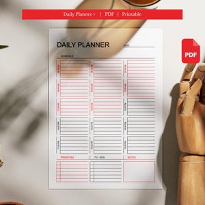 May include: A white daily planner with a red and black design. The planner includes sections for schedule, priorities, to-dos, and notes. The text "Daily Planner" is at the top. A red banner at the top reads "Daily Planner > | PDF | Printable".