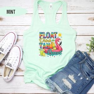 May include: A mint green tank top with the text "FLOAT Drink Tan Repeat" and a pink flamingo on a float. The flamingo is holding a cocktail umbrella and there are cocktails around it.