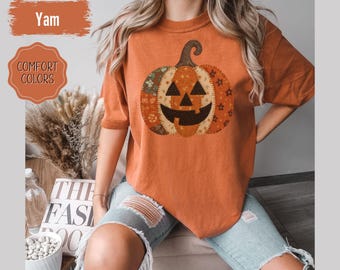 Puede incluir: Camiseta naranja con un diseño de calabaza de retazos. La calabaza tiene una cara sonriente y está hecha de varias telas estampadas. La camiseta tiene mangas cortas. El texto "Yam" y "Comfort Colors" son visibles.