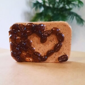 May include: A brown and beige bar of soap with a heart shape made of coffee beans embedded in the top.