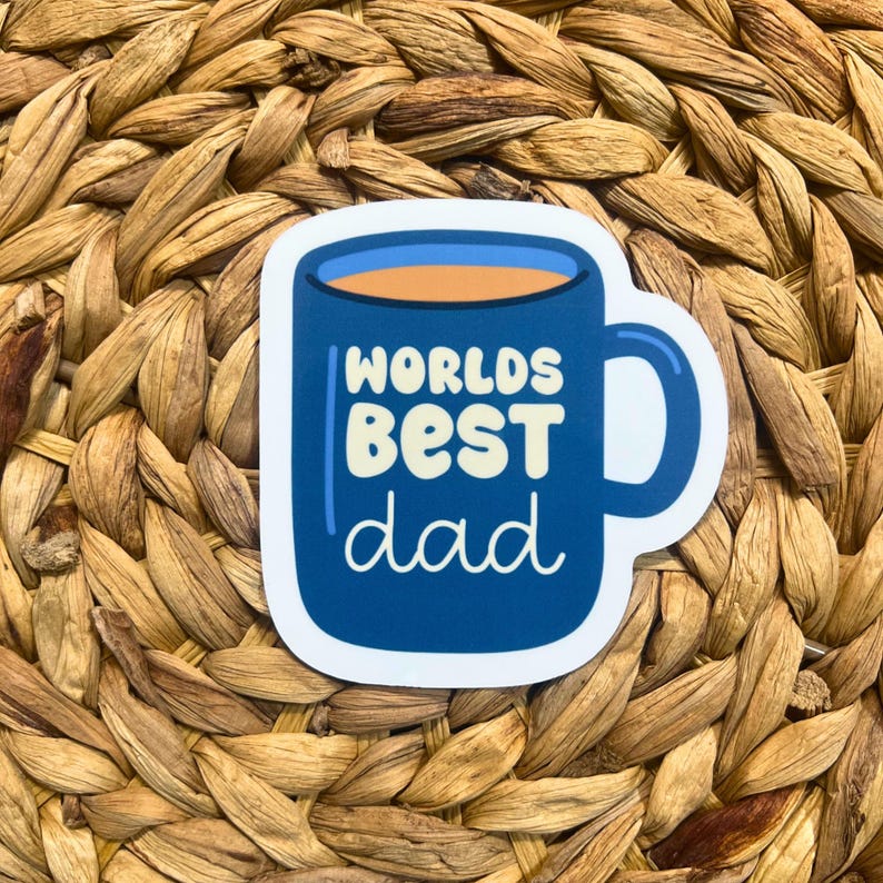 May include: A blue coffee mug sticker with the text "Worlds Best Dad" in yellow and white lettering.