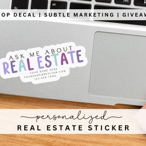 May include: A laptop sticker with the text "Ask Me About Real Estate" in colorful letters. The sticker also includes space for a name, website, and phone number. The sticker is on a silver laptop.
