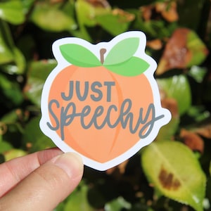 May include: A sticker featuring a cartoon peach with green leaves and the text "JUST Speechy" in gray cursive. The peach is orange with a white outline.