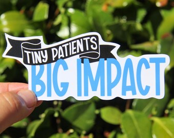 May include: A white sticker with the text "TINY PATIENTS" in white on a black banner, and "BIG IMPACT" in light blue. The sticker is held in front of a background of green leaves.
