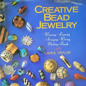 May include: A book titled "Creative Bead Jewellery" with a blue cover and colourful beads scattered across the front. The book title is in yellow text and the subtitle is "Weaving, Looming, Stringing, Wiring, Making Beads" in black text. The author's name, "Carol Taylor", is in white text.