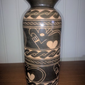 May include: A black ceramic vase with a brown design of stylized hearts and geometric patterns.