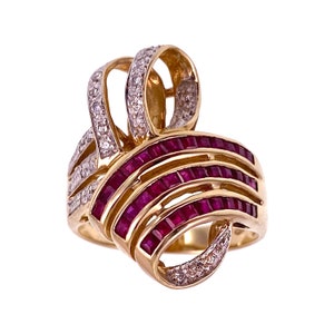 May include: A gold ring with a unique design featuring a cluster of red rubies and smaller diamonds. The rubies are set in a row, creating a band of color around the ring.