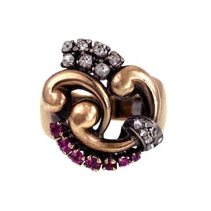 Puede incluir: Un anillo de oro con un diseño de espiral engastado con rubíes y diamantes.