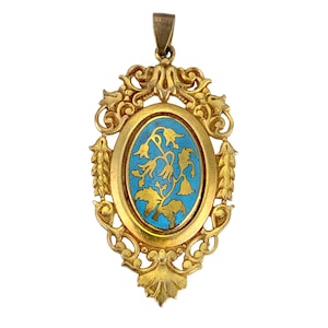 May include: A gold pendant with an oval blue enamel center featuring a gold floral design. The pendant is surrounded by a decorative gold frame.