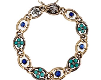 Puede incluir: Un brazalete de cadena de oro y plata con piedras preciosas azules y turquesas. El brazalete tiene un diseño único con eslabones ovalados y un cierre.