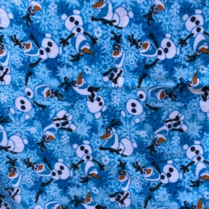 May include: Blue fabric with a repeating pattern of Olaf the snowman from the movie Frozen. Olaf is white with a carrot nose, black eyes, and a wide smile. The background is a light blue with a snowflake pattern.