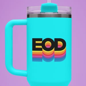 May include: A turquoise travel mug with a black handle and a black lid. The mug has a rainbow-colored graphic with the letters "EOD" in black.