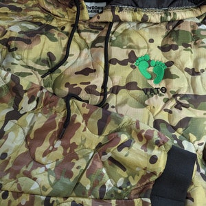 May include: Camouflage hooded jacket with a green footprint logo and the word "VATO" embroidered on the front.