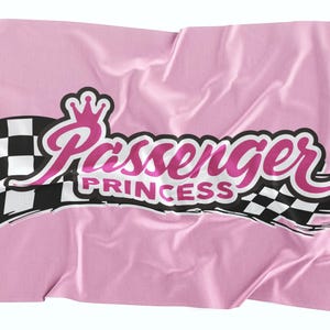 May include: Pink flag with a black and white checkered racing flag design and the text "Passenger Princess" in pink with a crown above the word "Passenger".