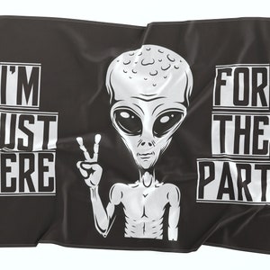 May include: Black and white flag with a cartoon alien holding up a peace sign. The text on the flag reads "I'm Just Here For The Party".