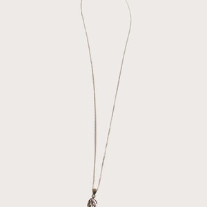 May include: A silver chain necklace with a small silver wing pendant.