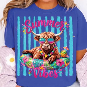 Peut inclure: T-shirt bleu royal avec un graphisme de vache des Highlands portant des lunettes de soleil et un collier de fleurs, se prélassant sur une bouée florale. Les mots "Summer Vibes" sont affichés en rose, avec une boisson à l'ananas. Le fond a des rayures bleues.