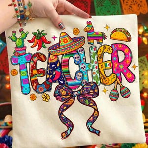 Peut inclure: Un coussin crème avec le mot "TEACHER" en lettres colorées et festives. Le design comprend un sombrero, un cactus et un nœud, sur le thème mexicain. Le coussin est tenu par une personne.