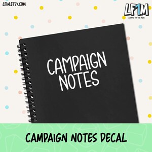 May include: A black spiral-bound notebook with the words "CAMPAIGN NOTES" in white script. The notebook is on a background with colorful polka dots. The text "CAMPAIGN NOTES DECAL" is at the bottom.