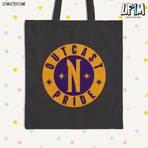 Puede incluir: Bolso tote negro con un diseño gráfico circular. El diseño presenta la palabra "OUTCAST" en dorado, arqueada en la parte superior, y "PRIDE" en la parte inferior. Una gran "N" dorada está en el centro, con un fondo morado. El bolso tiene dos asas negras.