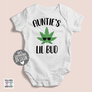 May include: White baby onesie with the text "Auntie's Lil Bud" and a green marijuana leaf with sunglasses.
