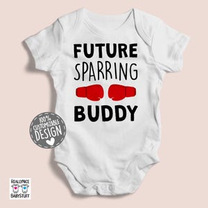 May include: White baby bodysuit with black text that reads "Future Sparring Buddy" and a graphic of two red boxing gloves.