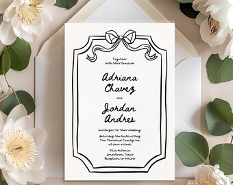 Könnte beinhalten: Eine Hochzeitseinladung mit einem schwarz umrandeten Rahmen und Schleifendesign. Die Einladung enthält die Namen Adriana Chavez und Jordan Andres sowie Hochzeitsdetails. Die Einladung ist von weißen Blumen und Grün umgeben.
