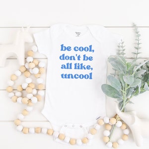 Puede incluir: Un body blanco para bebé con texto azul que dice "be cool, don't be all like, uncool".