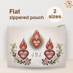 May include: A flat, zippered pouch with a gold zipper. The pouch features a central heart design with flames, a cross, and the initials "JMJ". Floral and rose accents surround the heart. The text "Flat zippered pouch" and "2 sizes" are also visible.