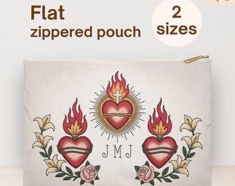 May include: A flat, zippered pouch with a gold zipper. The pouch features a central heart design with flames, a cross, and the initials "JMJ". Floral and rose accents surround the heart. The text "Flat zippered pouch" and "2 sizes" are also visible.