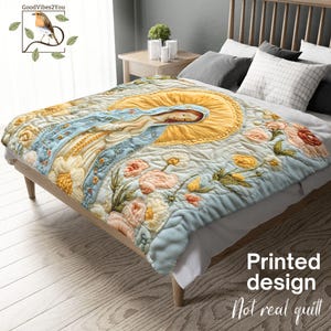 May include: A light blue quilt with a printed design featuring a religious figure with a yellow halo and floral embroidery. The quilt is draped over a wooden bed frame. The text "Printed design Not real quilt" is visible.