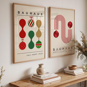 May include: Two framed wall art prints featuring Bauhaus exhibition posters. The left print displays abstract shapes and Christmas ornaments with the text BAUHAUS and JULI-SEPT 1923. The right print shows red line arches and ornaments with the text BAUHAUS Ausstellung 1923.