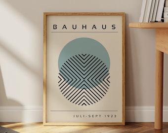 May include: A framed poster with a minimalist design featuring a blue circle with black and white stripes inside. The poster has the text "BAUHAUS" and "JULI-SEPT 1923" printed on it.