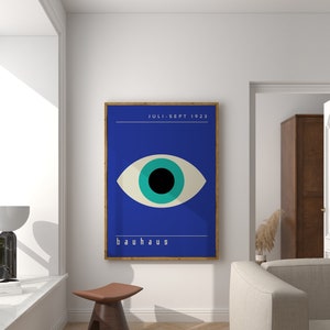 May include: A framed poster with a blue background and a large, stylized eye with a black pupil and a turquoise iris. The text "JULI-SEPT 1923" is at the top of the poster, and the word "bauhaus" is at the bottom.