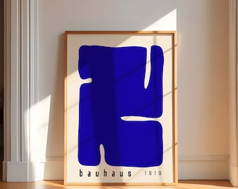 May include: A framed poster featuring an abstract blue shape on a cream background. The poster is labelled "bauhaus 1919" at the bottom.