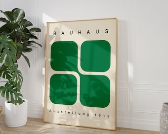 May include: A framed poster with a minimalist design featuring the word "BAUHAUS" in black text and four green squares arranged in a grid pattern. The text "Ausstellung 1919" appears below the squares.