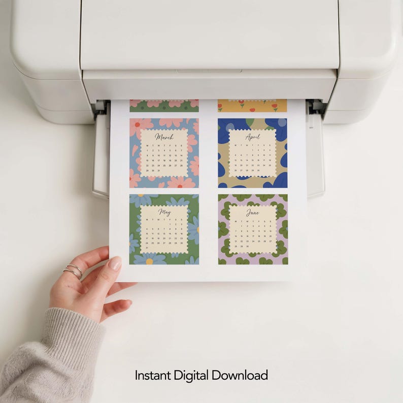 May include: A white printer outputting a sheet of paper featuring four calendar months: March, April, May, and June. Each month is displayed within a scalloped-edge square frame set against a background of colorful, stylized floral patterns.